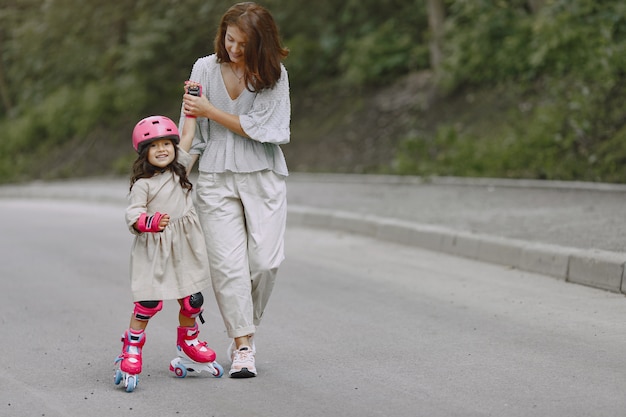 Familie in een zomerpark. Moeder in een blouse. Meisje met een roller.