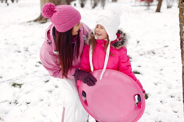 Familie in gebreide wintermutsen op familiekerstvakantie. Vrouw en meisje in een park. Mensen spelen.