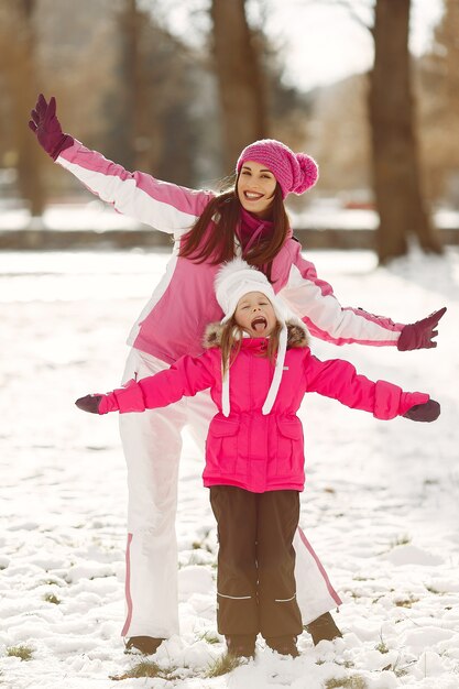 Familie in gebreide wintermutsen op familiekerstvakantie. Vrouw en meisje in een park. Mensen spelen.