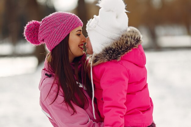 Familie in gebreide wintermutsen op familiekerstvakantie. Vrouw en meisje in een park. Mensen spelen.