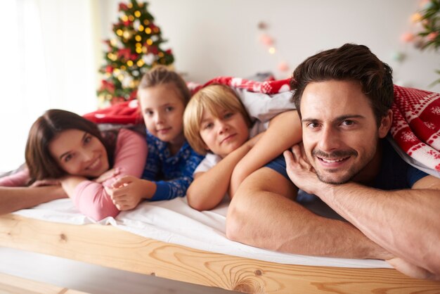 Familie liggend in bed in de kersttijd