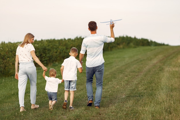 Familie loopt in een veld en speelt met speelgoedvliegtuig