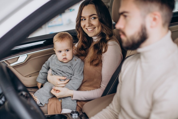 Familie met bbay girl die een auto kiest in een autosalon