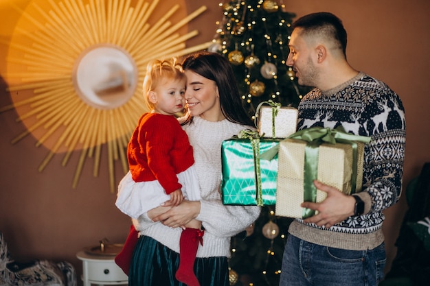 Familie met dochtertje door kerstboom uitpakken geschenkdoos