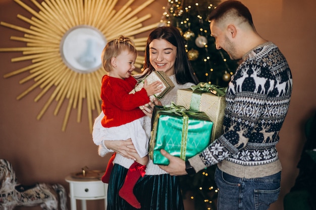 Familie met dochtertje door kerstboom uitpakken geschenkdoos