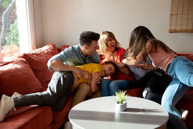 Familie met ouders en kinderen die samen plezier hebben op de bank