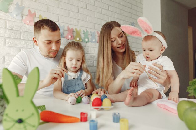 Familie met twee jonge geitjes in een keuken die aan Pasen voorbereidingen treft