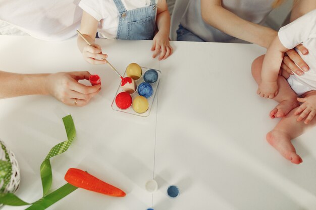 Familie met twee jonge geitjes in een keuken die aan Pasen voorbereidingen treft