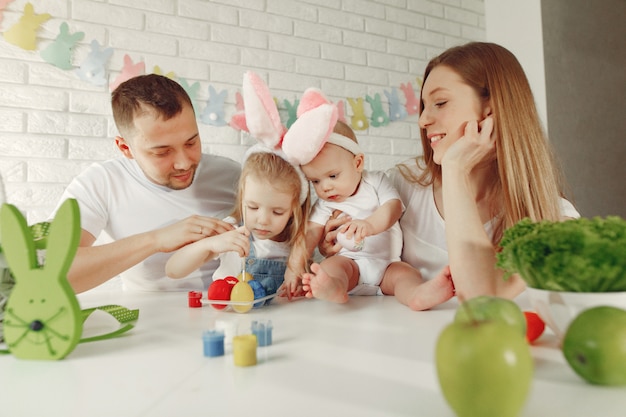 Familie met twee jonge geitjes in een keuken die aan Pasen voorbereidingen treft