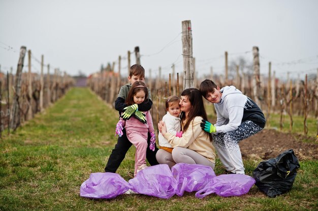 Familie met vuilniszak die afval verzamelt tijdens het schoonmaken in de wijngaarden Milieubehoud en ecologische recycling