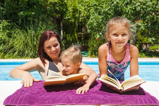 Familie ontspannen in zwembad met boeken