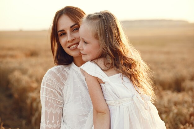 Familie op een zomergebied. Sensuele foto. Schattig klein meisje. Vrouw in een witte jurk.