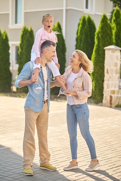 Familie op wandeling. Papa draagt een meisje op zijn schouders tijdens een gezinswandeling