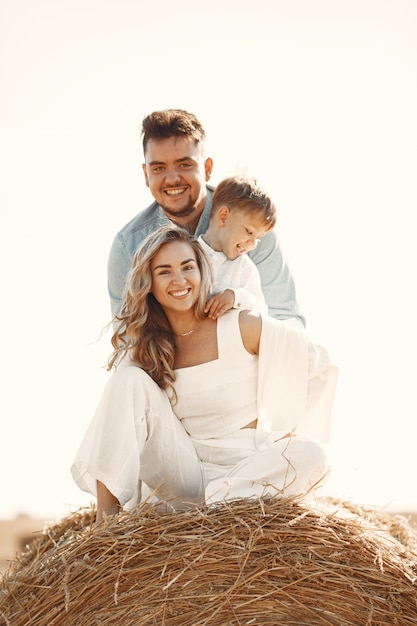 Familie spelen met zoontje in een tarweveld op zonsondergang. Het concept van zomervakantie. Familie tijd samen doorbrengen op de natuur.