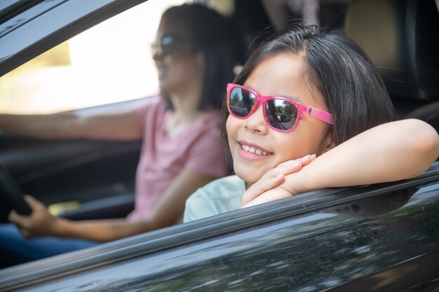 Familie vakantie vakantie, gelukkige familie op een road trip in hun auto, moeder auto rijden terwijl haar dochter naast zit, moeder en dochter reizen. zomerrit met de auto.