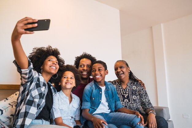 Familie van meerdere generaties die selfie met telefoon thuis nemen.