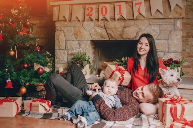 Familie zittend op de vloer met bruine geschenken en een kerstboom