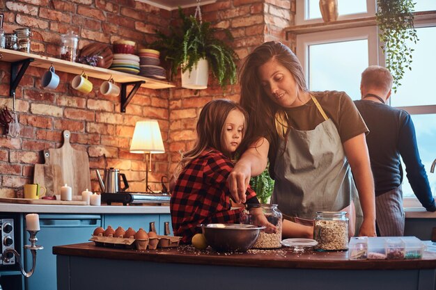 Familieconcept. Gelukkig moeder koken met haar dochtertje in loft-stijl keuken 's ochtends.