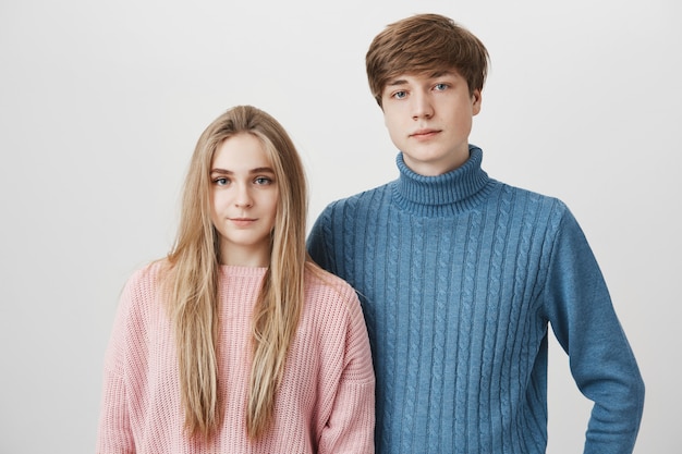 Familieportret van Kaukasisch jong paar in sweaters. De blonde jongen en het meisje met blauwe ogen kijken met kalme en tevreden uitdrukkingen