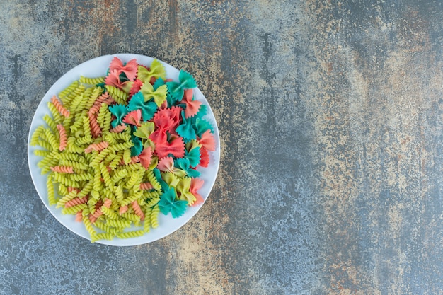 Farfalle en fusilli pasta op de plaat, op het marmeren oppervlak.