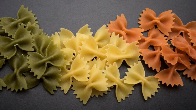 Farfalle verse pasta in groen; gele en oranje kleuren boven keukenwerkblad