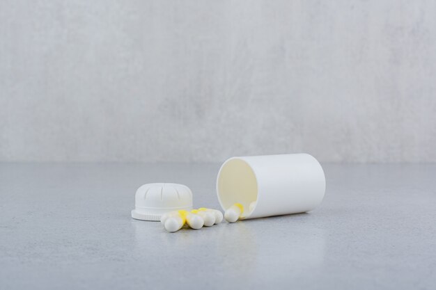 Farmaceutische capsules uit witte plastic container.