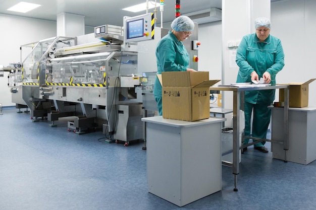 Farmaceutische technici werken in steriele werkomstandigheden in farmaceutische fabriek Wetenschappers dragen beschermende kleding