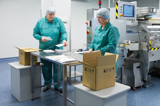 Farmaceutische technici werken in steriele werkomstandigheden in farmaceutische fabriek Wetenschappers dragen beschermende kleding
