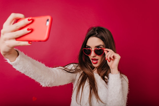 Fascinerend meisje met rode manicure die foto van zichzelf neemt