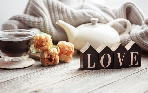 Feestelijk huisstilleven met bloemen, een kopje thee en een theepot op een houten ondergrond close-up.