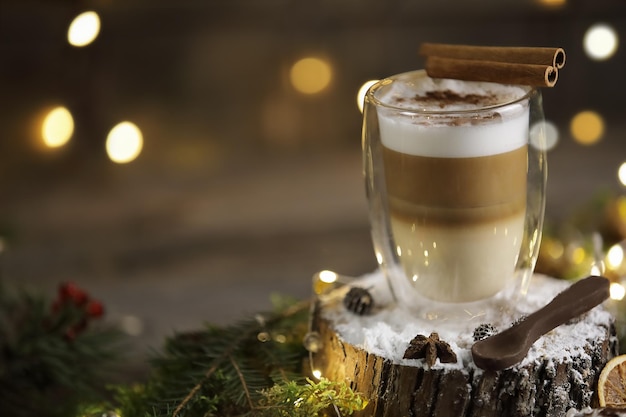 Feestelijke latte in een glazen kom met chokolate-lepel op de stomp op een donkere houten ondergrond met verlichting