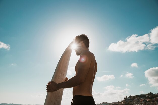 Felle zon achter man met surfplank