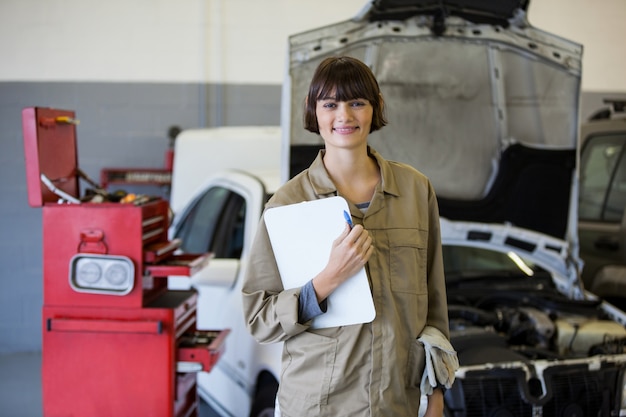 Female mechanic glimlachend in de camera en het bedrijf klembord