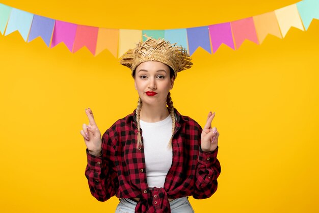 Festa junina blond schattig meisje in strohoed Braziliaans festival met kleurrijke vlaggen die vingers kruisen