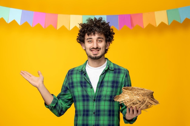 Festa junina jonge, schattige kerel die een strohoed en een kleurrijk vlaggen braziliaans festival afzet