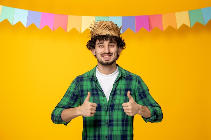 Gratis Foto festa junina jonge schattige kerel in strohoed en kleurrijke vlaggen braziliaans festival opgewonden