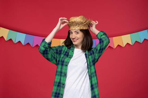 Gratis foto festa junina mooi schattig meisje met een strohoed en viert een braziliaans festival dat de hoed aanraakt