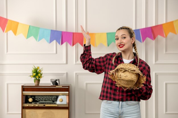 Festa junina schattig meisje dat strohoed afdoet aan Braziliaanse midzomer met kleurrijke retro-radiovlaggen