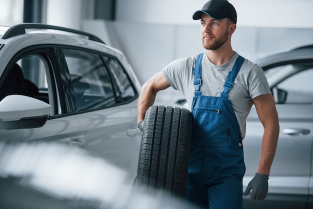 Fijn voelen. Monteur met een band bij de reparatiegarage. Vervanging van winter- en zomerbanden