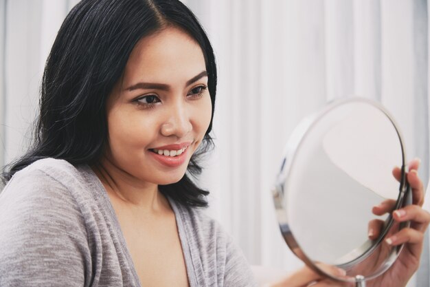 Filipijnse vrouw die spiegel bekijkt