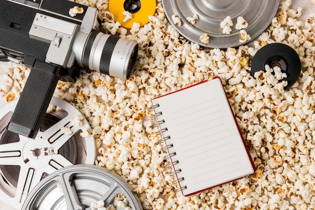 Filmrol en camcordercamera met spiraalvormige blocnote op popcorn