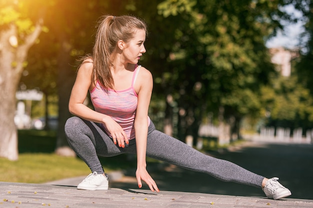 Fit fitness vrouw doet rekoefeningen buiten in het park