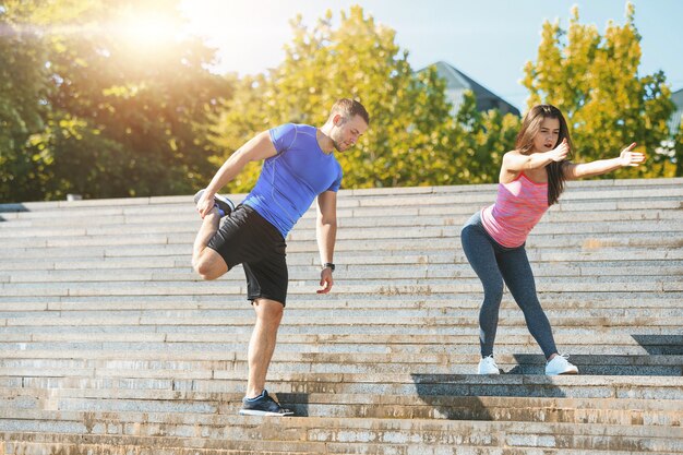 Fit fitness vrouw en man doen rekoefeningen buiten in het park