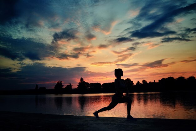 Fit sportvrouw oefenen op zonsondergang