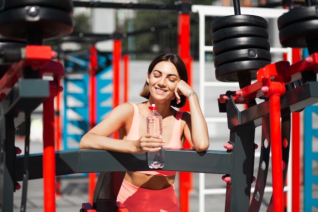 Fit vrouw in roze sportkleding buiten passen met fles water