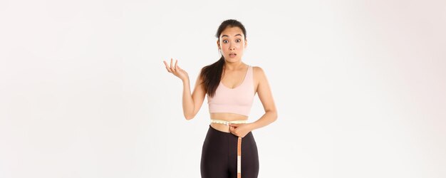 Fitness gezonde levensstijl en welzijn concept verrast Aziatisch meisje op dieet sportvrouw wrap maatregel