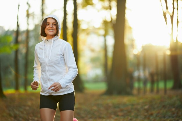 Fitness vrouw in jas met capuchon die buiten traint