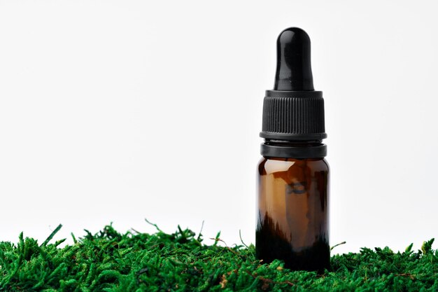 Fles aromatische olie voor kruidengeneeskunde onder natuurlijk groen mos, close-up Premium Foto