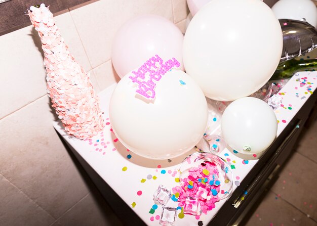 Fles bedekt met roze confetti tegen witte ballon