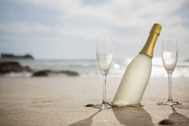 Fles champagne en twee glazen op zand